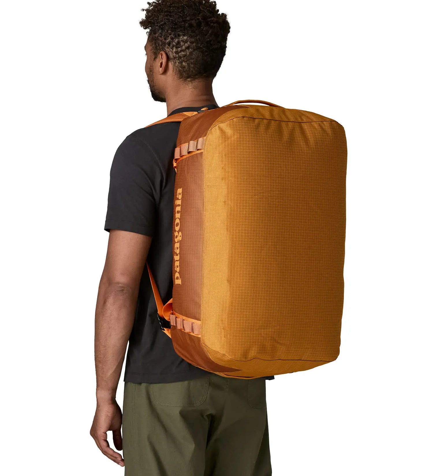 Back of man carrying the Patagonia black hole 55L duffel bag in Cinnamon brown showing the protective panel on the underside of the bag
