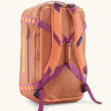 Back of Patagonia black hole 55l duffel bag in bright orange with matching shoulder straps and extra purple carry handles