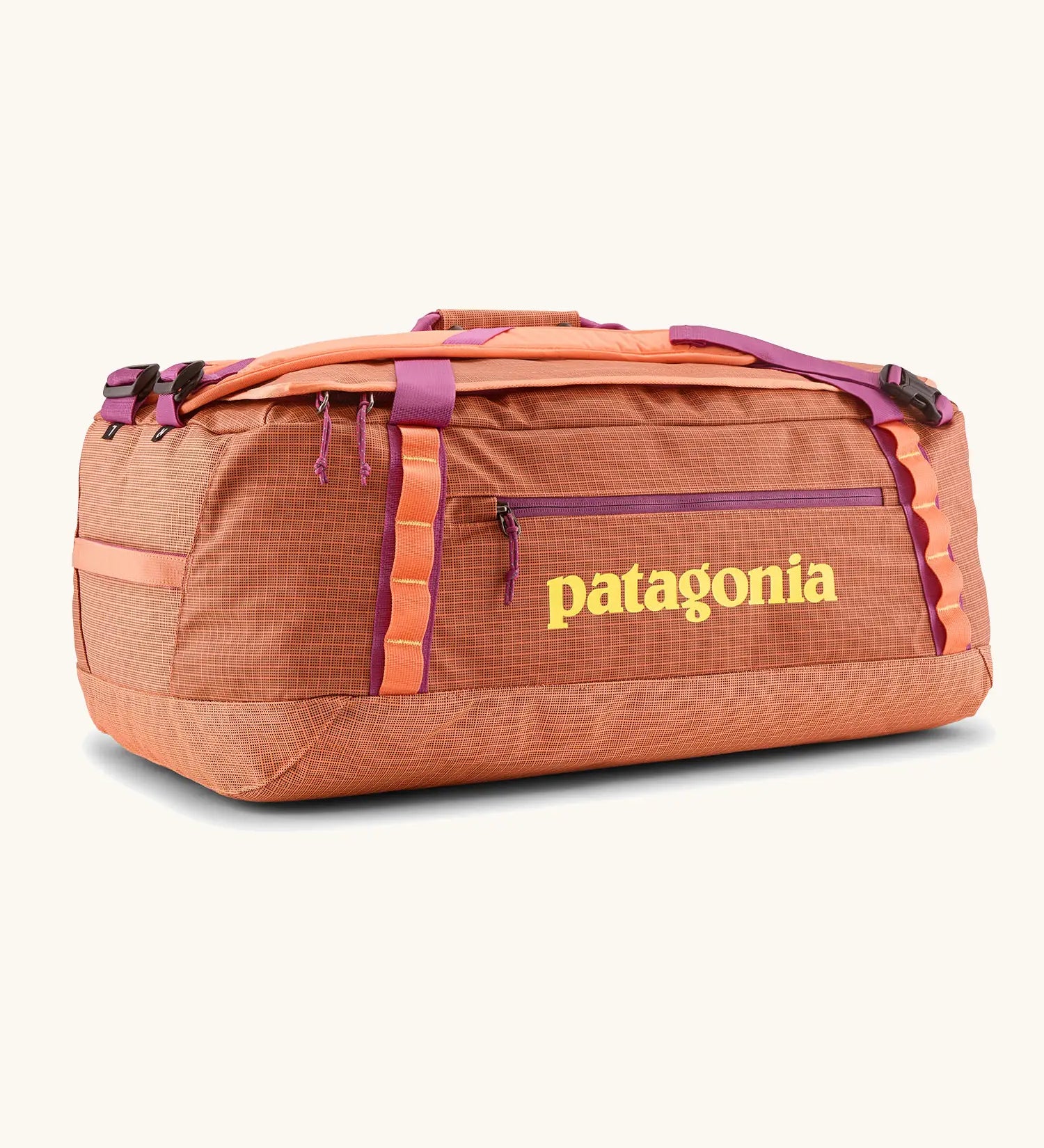 Patagonia black hole 55l duffel bag in bright orange with purple zip details, straps and yellow printed logo on front panel 
