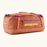 Patagonia black hole 55l duffel bag in bright orange with purple zip details, straps and yellow printed logo on front panel 