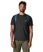Front of man carrying the Patagonia black hole 55L duffel bag in dark teal using the padded shoulder straps