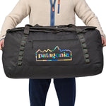 A person holding the Patagonia Black Hole Duffel 100L Ink Black in their hands, showing the size