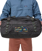 A person holding the Patagonia Black Hole Duffel 55L  Ink Black in their hands to show the size