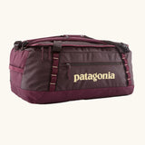 Patagonia black hole 55L duffel bag in Berry Fig with yellow details and Patagonia printed logo.