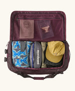 Patagonia Black Hole duffle 70L in berry fig, open to show storage space and zipped mesh pocket. 