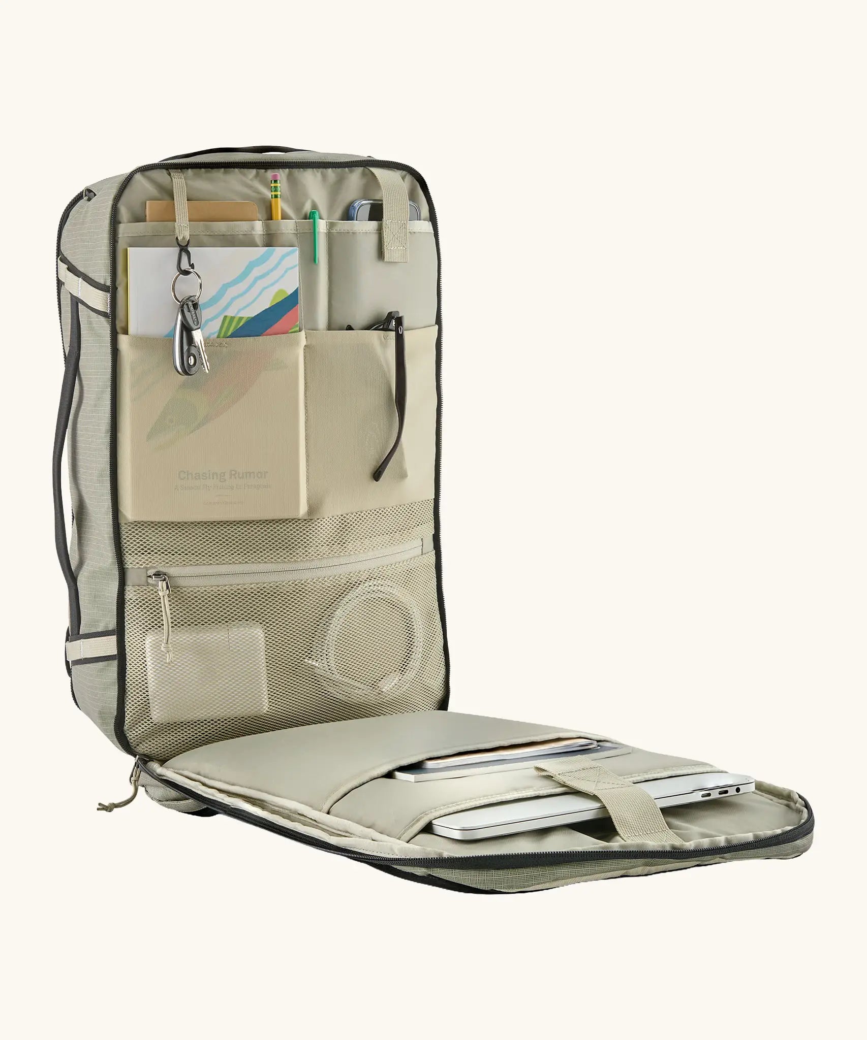 An open Patagonia 30 litre black hole weather resistant travel backpack beige showing items inside different compartments 