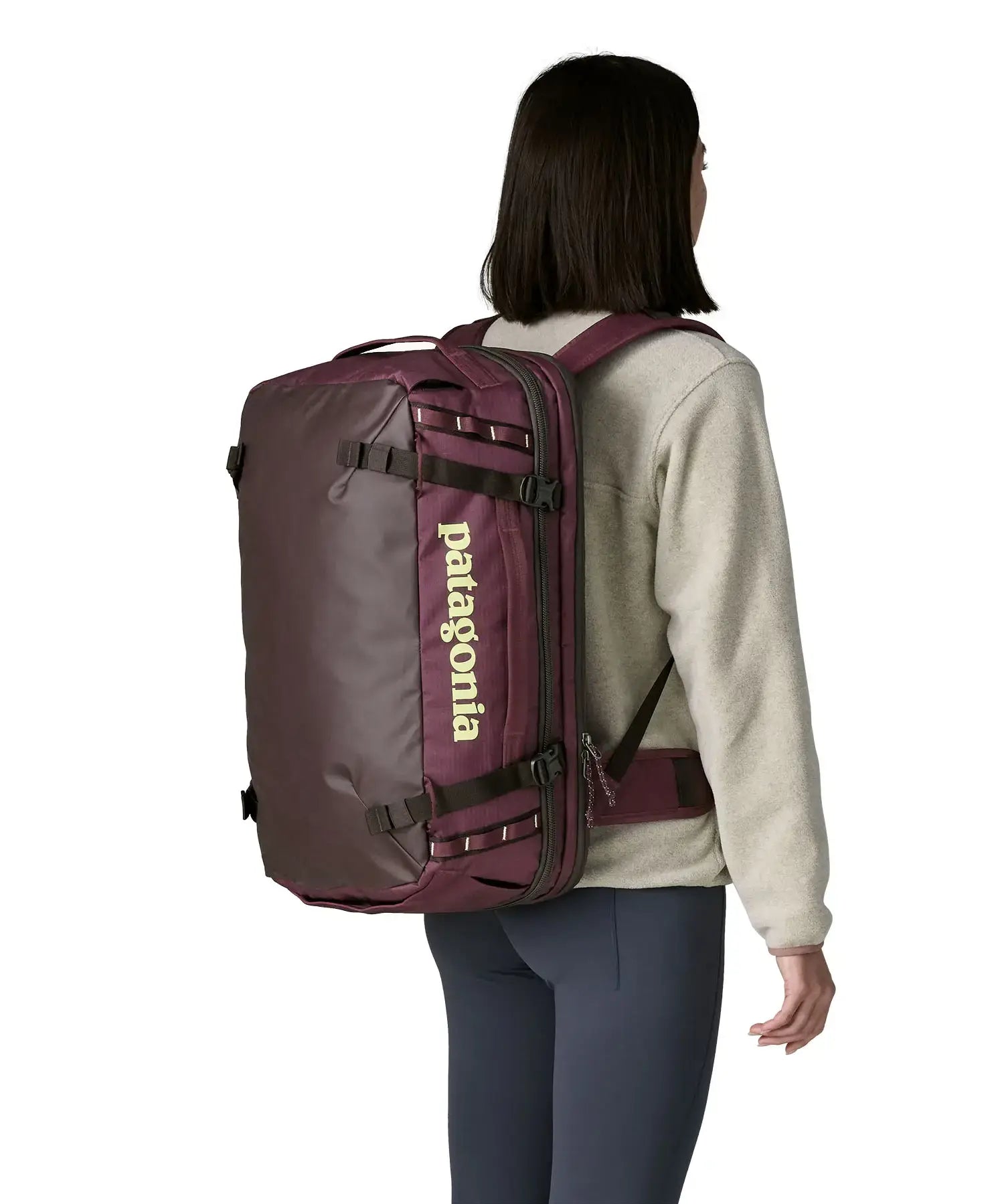 An adult carrying a  Patagonia 45 litre black hole travel backpack in maroon using the shoulder and hip straps