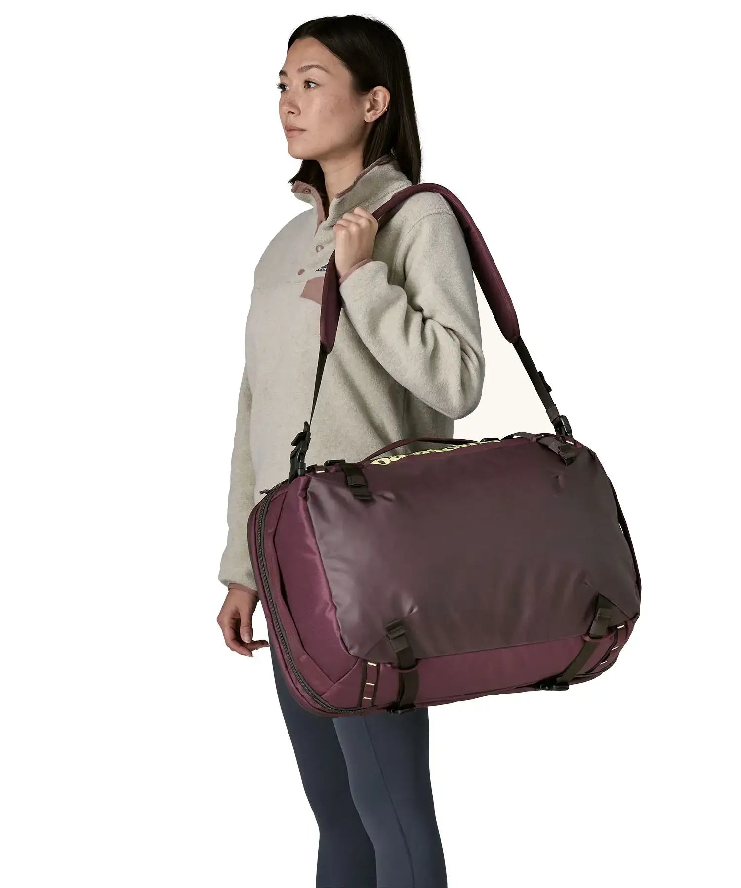 An adult carrying a Patagonia 45 litre black hole travel backpack in maroon over the shoulder 