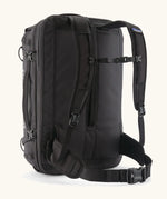 Back of Patagonia 45 litre black hole weather resistant travel backpack in all black showing padded shoulder and hip straps with buckle fasteners