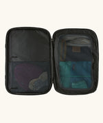 An open Patagonia 45 litre black hole weather resistant travel backpack in all black showing clothes inside different compartments 