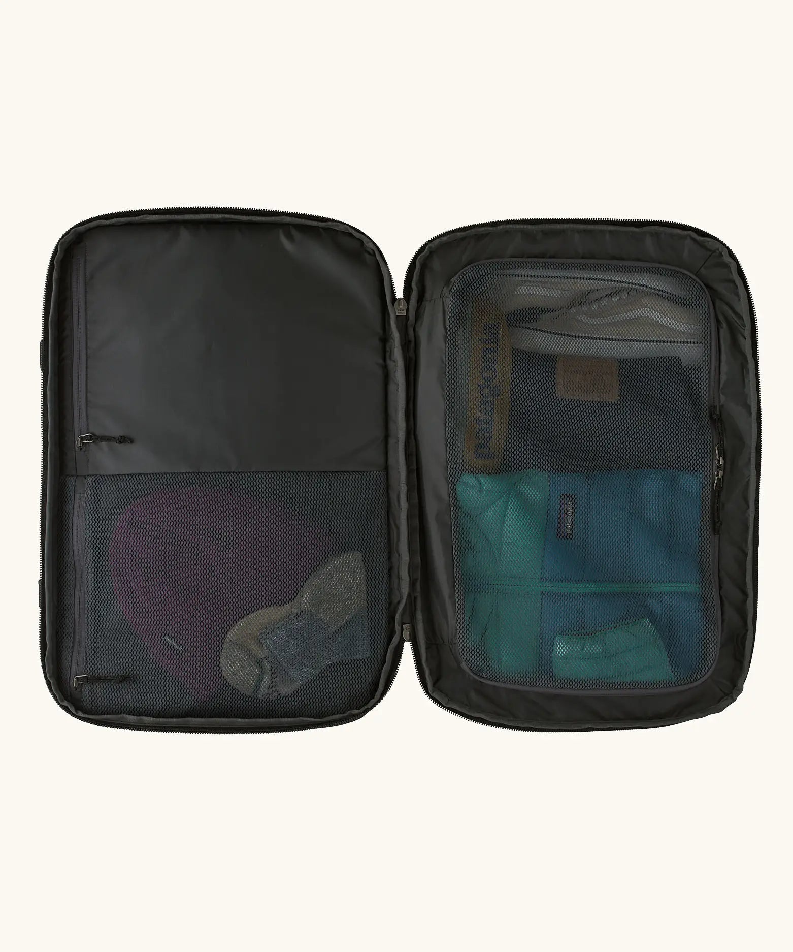 An open Patagonia 45 litre black hole weather resistant travel backpack in all black showing clothes inside different compartments 