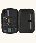 An open Patagonia 45 litre black hole weather resistant travel backpack in all black showing items inside different compartments 
