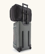 Patagonia 45 litre black hole weather resistant travel backpack in all black on top of a wheeled duffel bag through a loop on the back