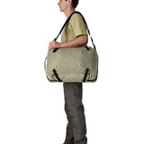 An adult carrying a Patagonia 45 litre black hole travel backpack in beige over the shoulder using the crossbody strap