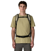 Front of adult carrying a Patagonia 45 litre black hole travel backpack in beige showing the shoulder and hip strap with buckle fasteners