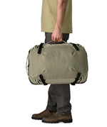 Side of an adult carrying a Patagonia 45 litre black hole travel backpack in beige over the shoulder using the carry handle 