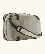 Patagonia 45 litre black hole weather resistant travel backpack in beige with black trim showing padded crossbody strap