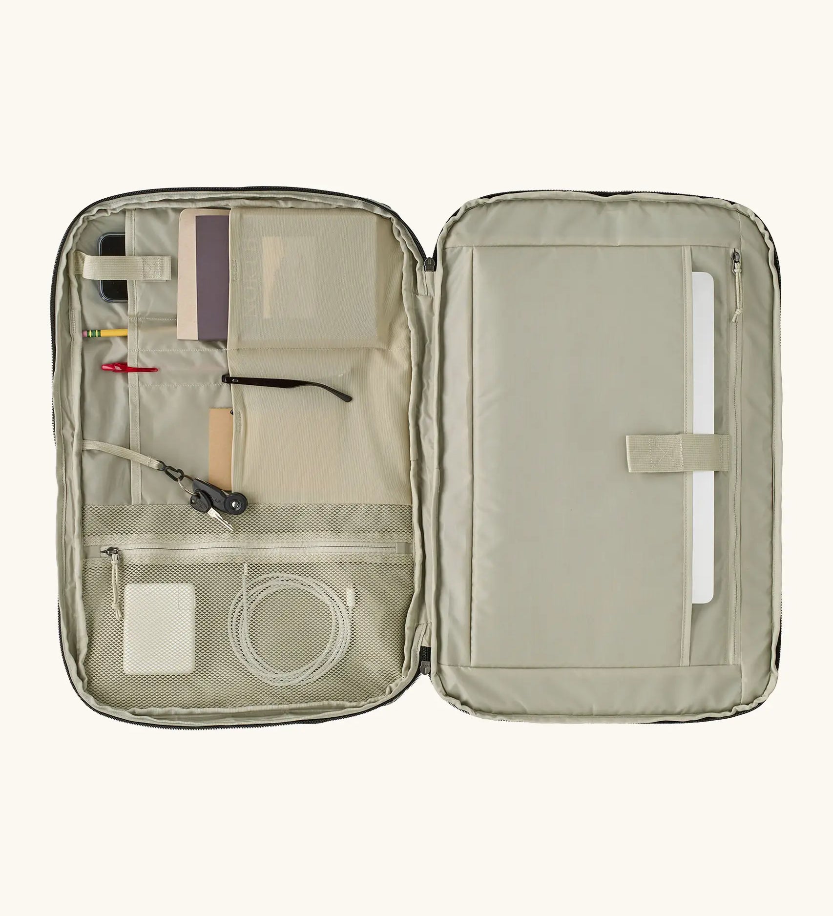 An open Patagonia 45 litre black hole weather resistant travel backpack beige showing items inside different compartments 