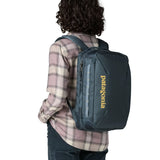 Back of woman with a Patagonia 22 litre black hole  micro travel backpack in teal showing extra loops for attaching items