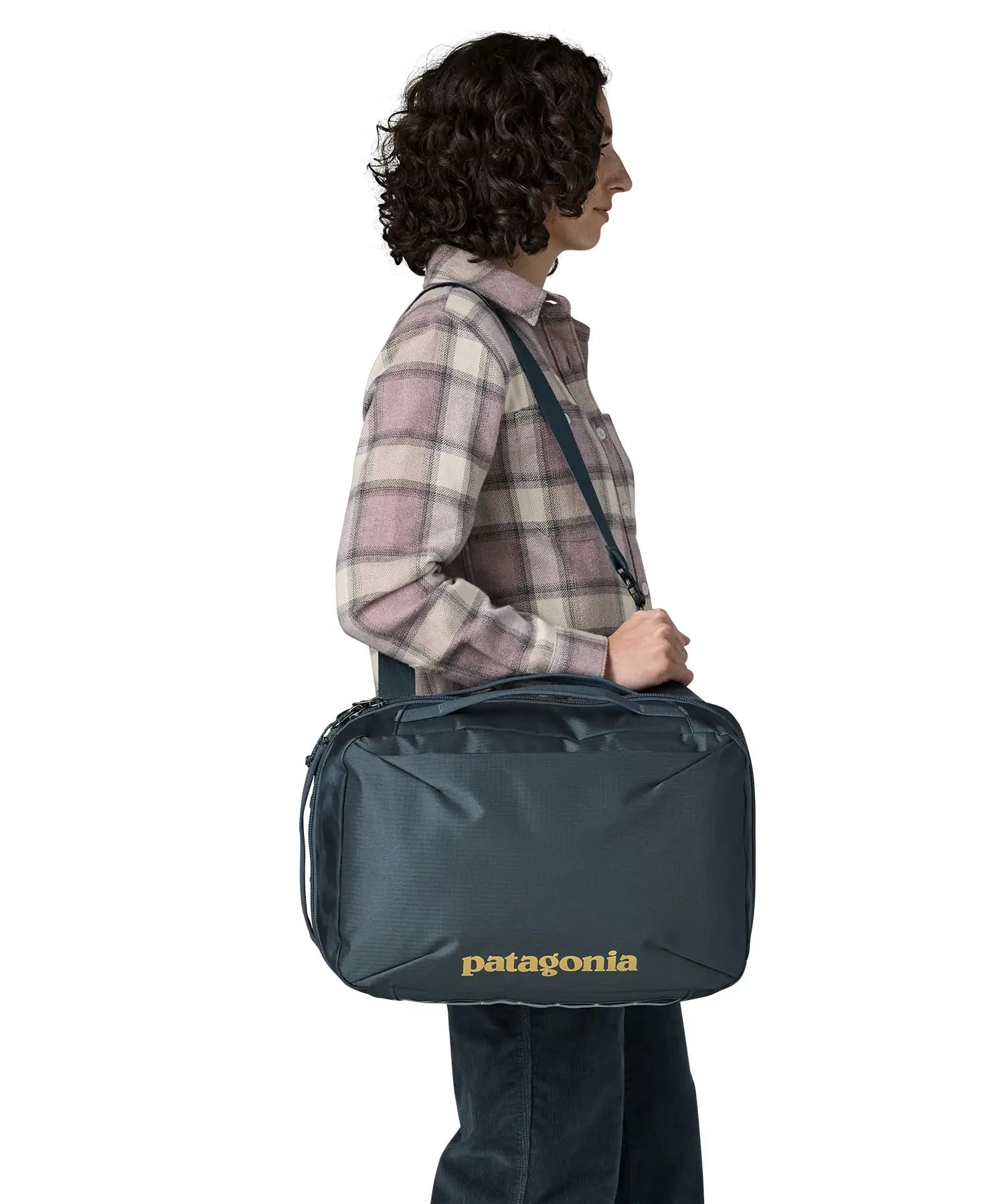 Woman carrying a Patagonia 22 litre black hole micro travel backpack in teal using the crossbody strap