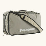 Patagonia 30 litre black hole weather resistant travel backpack in beige with black trim showing padded crossbody strap