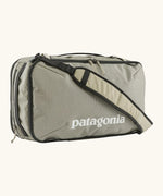 Patagonia 30 litre black hole weather resistant travel backpack in beige with black trim showing padded crossbody strap