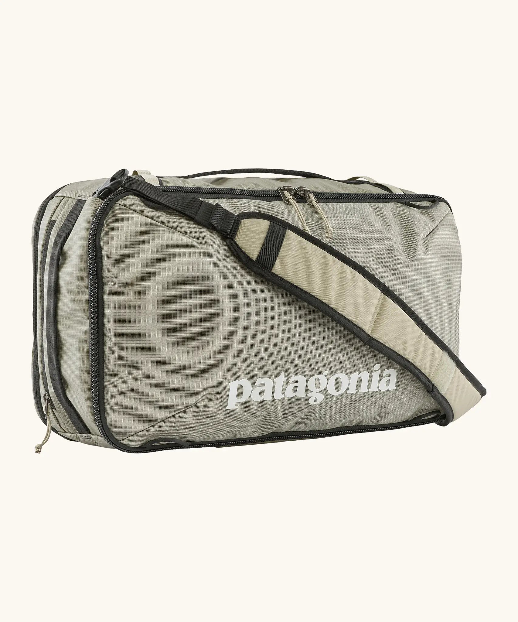 Patagonia 30 litre black hole weather resistant travel backpack in beige with black trim showing padded crossbody strap