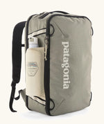 Patagonia 30 litre black hole travel backpack in beige with black trim  showing the mesh side pocket with a bottle inside