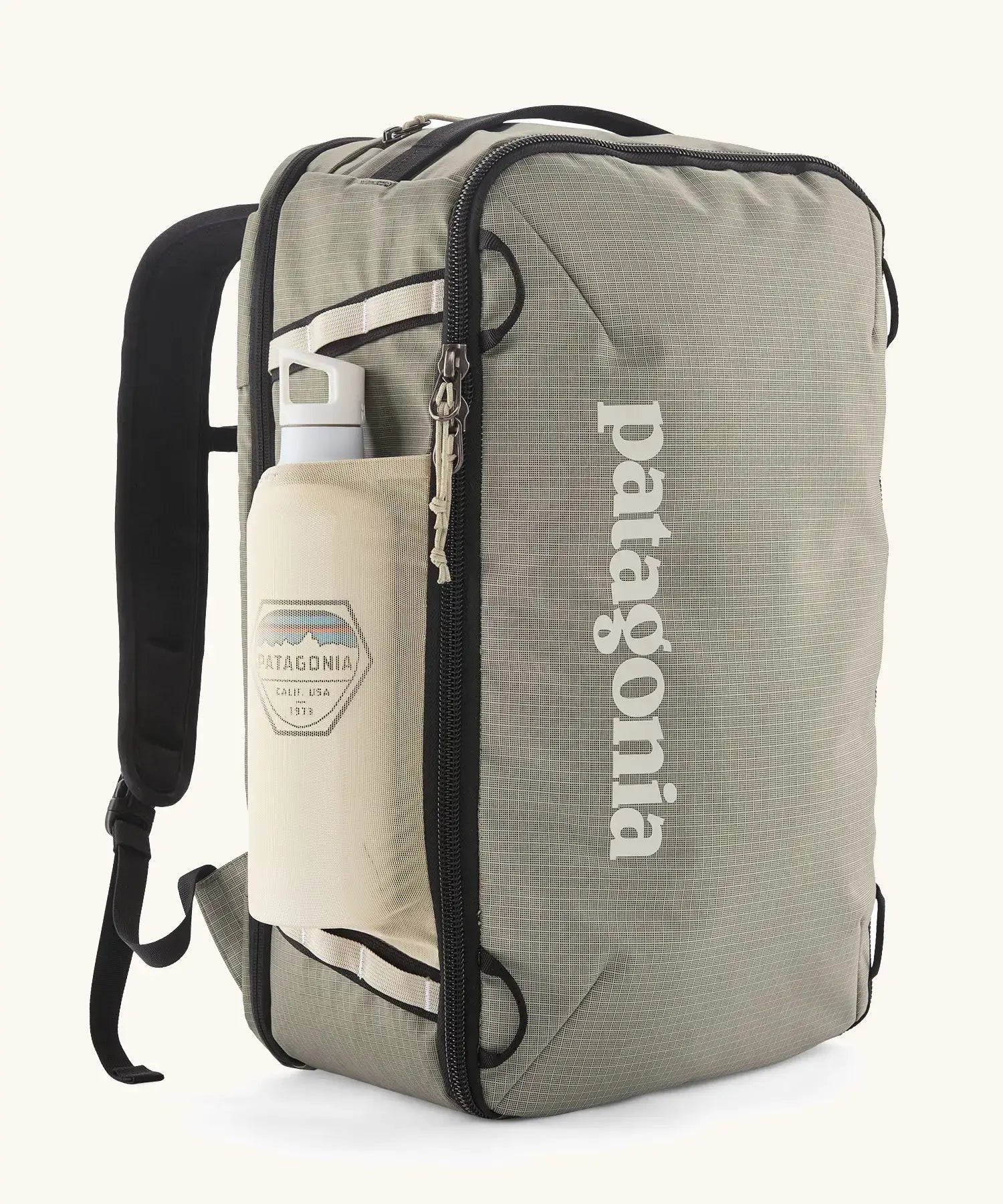 Patagonia 30 litre black hole travel backpack in beige with black trim  showing the mesh side pocket with a bottle inside