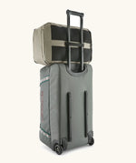 Patagonia 30 litre black hole weather resistant travel backpack in beige on top of a wheeled duffel bag through a loop on the back