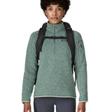 An adult facing forward and wearing the Patagonia Black Hole Backpack 25 litre capacity backpack in all black available at Babipur showing the buckle clip holding the padded shoulder straps close together 