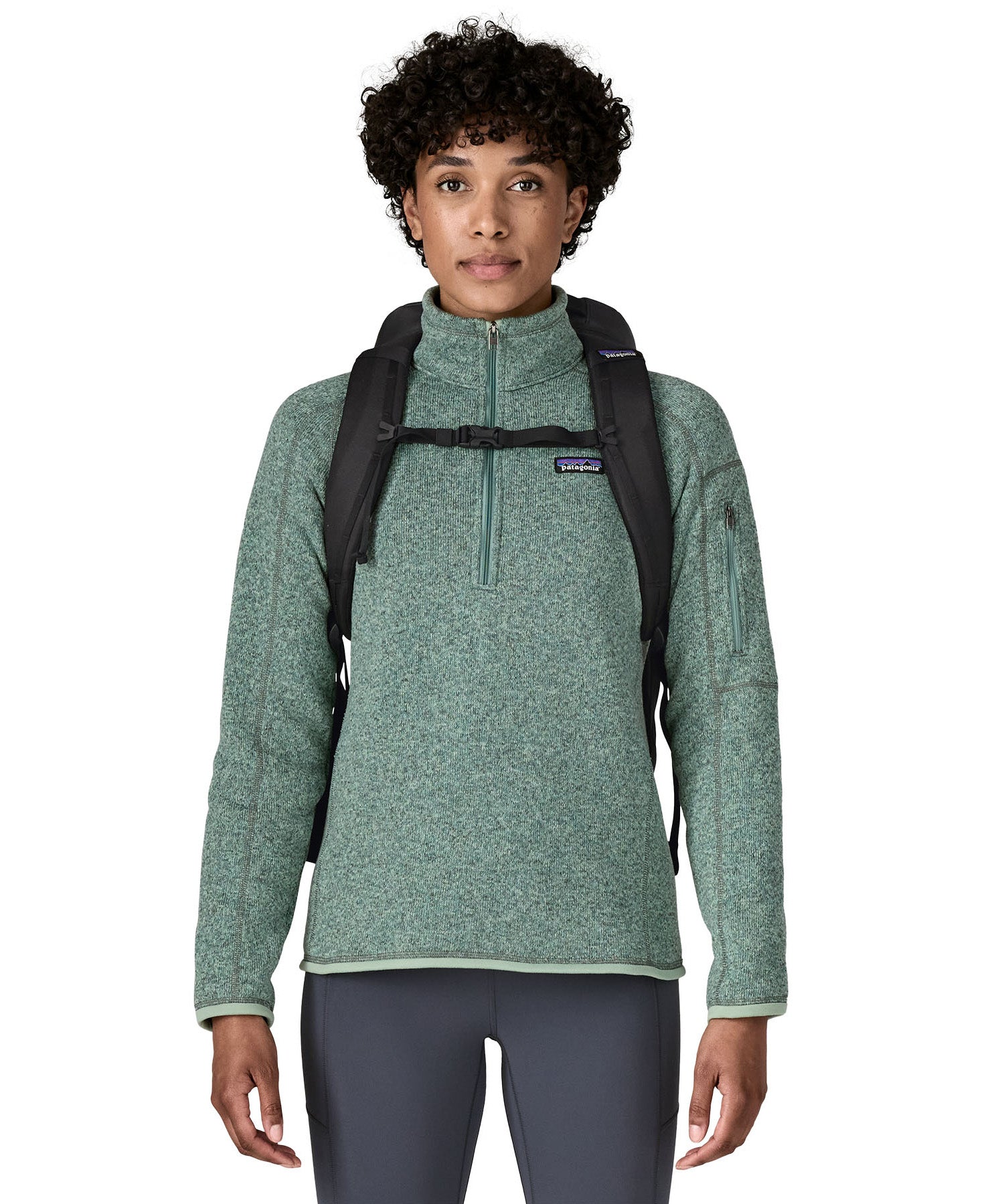 An adult facing forward and wearing the Patagonia Black Hole Backpack 25 litre capacity backpack in all black available at Babipur showing the buckle clip holding the padded shoulder straps close together 