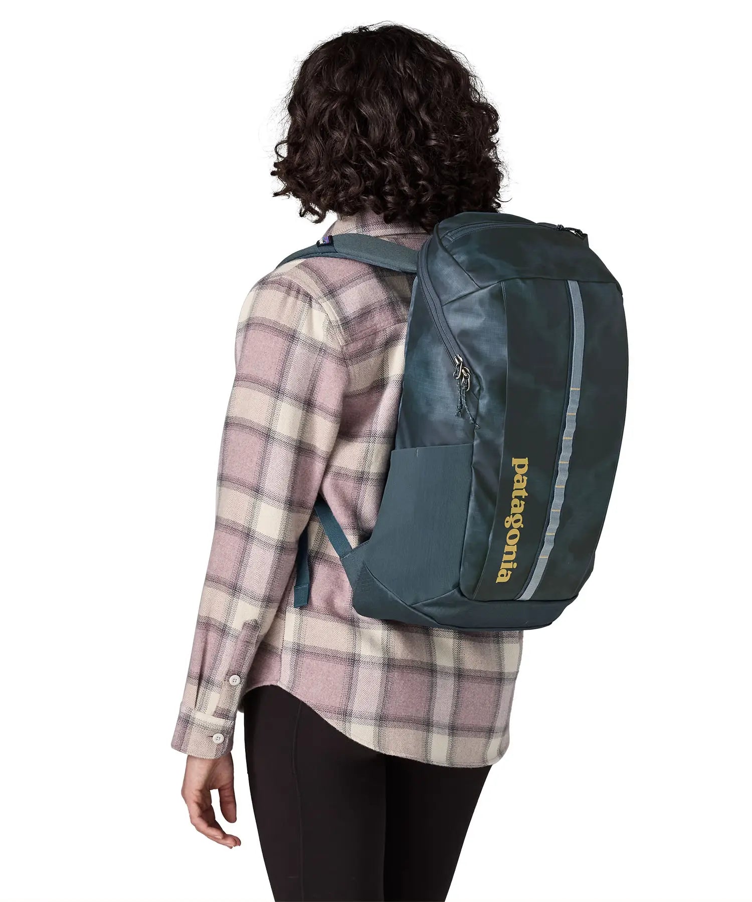 Woman carrying a Patagonia 100% recycled polyester black hole 25 litre backpack in teal on the back 