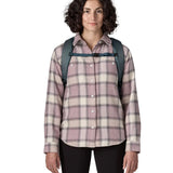 Front of woman carrying a Patagonia 100% recycled polyester black hole 25 litre backpack in teal showing the chest strap fastened