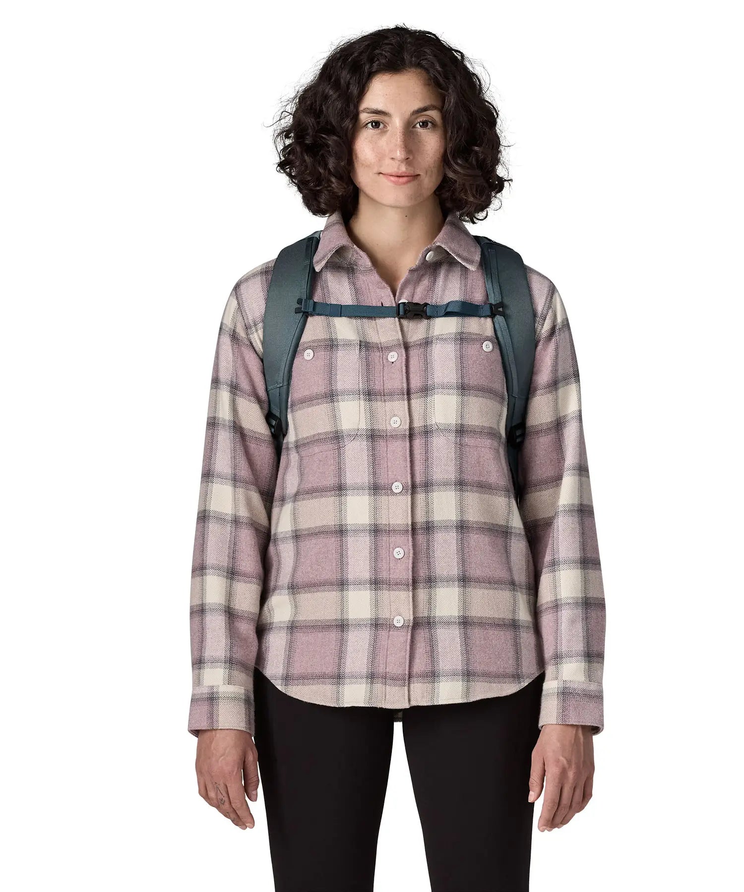 Front of woman carrying a Patagonia 100% recycled polyester black hole 25 litre backpack in teal showing the chest strap fastened