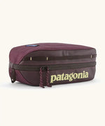 Patagonia compact 3L black hole cube travel bag in maroon. Showing a zip fastener with the brand name on the top panel