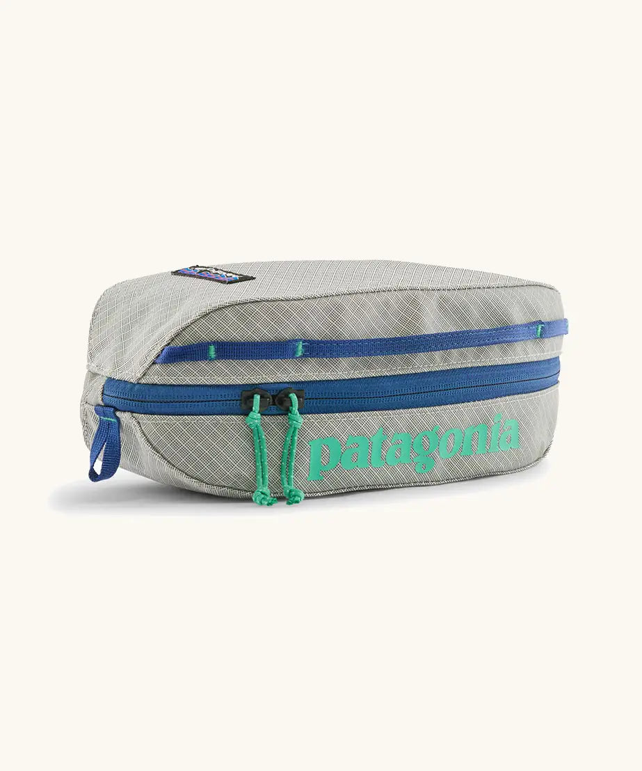 Patagonia 3L black hole cube travel bag in light grey and blue trim. Showing a zip fastener with the brand name on the top panel