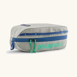Patagonia 3L black hole cube travel bag in light grey and blue trim. Showing a zip fastener with the brand name on the top panel