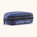 Patagonia 3L black hole cube travel bag in blue with black trim. Showing a zip fastener with the brand name on the top panel