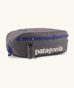 Patagonia 3L black hole cube travel bag in dark grey and blue trim. Showing a zip fastener with the brand name on the top panel