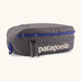 Patagonia 3L black hole cube travel bag in dark grey and blue trim. Showing a zip fastener with the brand name on the top panel