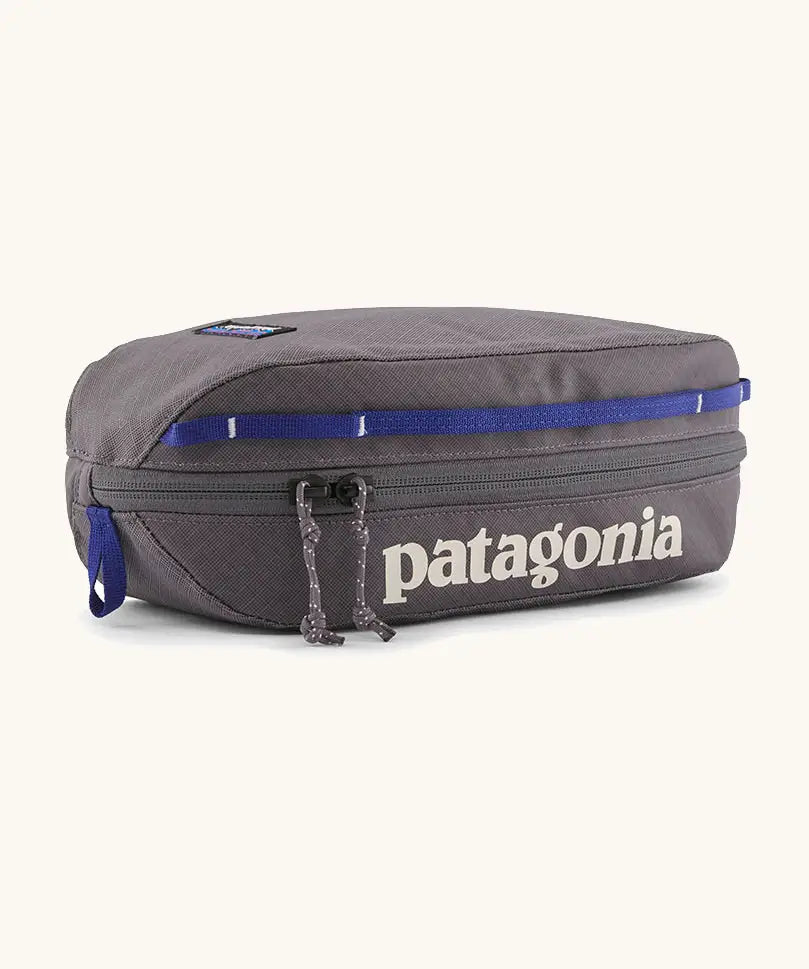 Patagonia 3L black hole cube travel bag in dark grey and blue trim. Showing a zip fastener with the brand name on the top panel