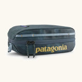 Patagonia 3L black hole cube travel bag in teal and light blue trim. Showing a zip fastener with the brand name on the top panel