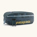 Patagonia 3L black hole cube travel bag in teal and light blue trim. Showing a zip fastener with the brand name on the top panel