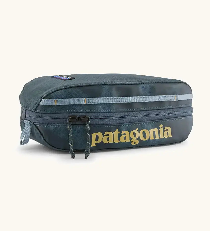 Patagonia 3L black hole cube travel bag in teal and light blue trim. Showing a zip fastener with the brand name on the top panel
