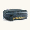 Patagonia 3L black hole cube travel bag in teal and light blue trim. Showing a zip fastener with the brand name on the top panel