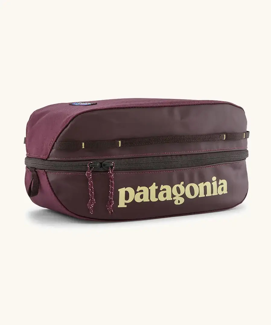 Patagonia black hole 6 litre cube bag in maroon with a double zip fastener showing the brand print on front panel