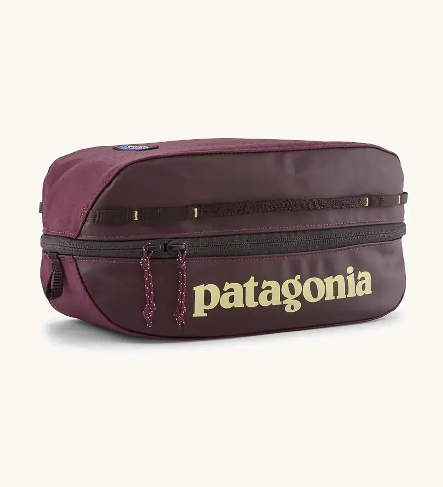 Patagonia black hole 6 litre cube bag in maroon with a double zip fastener showing the brand print on front panel