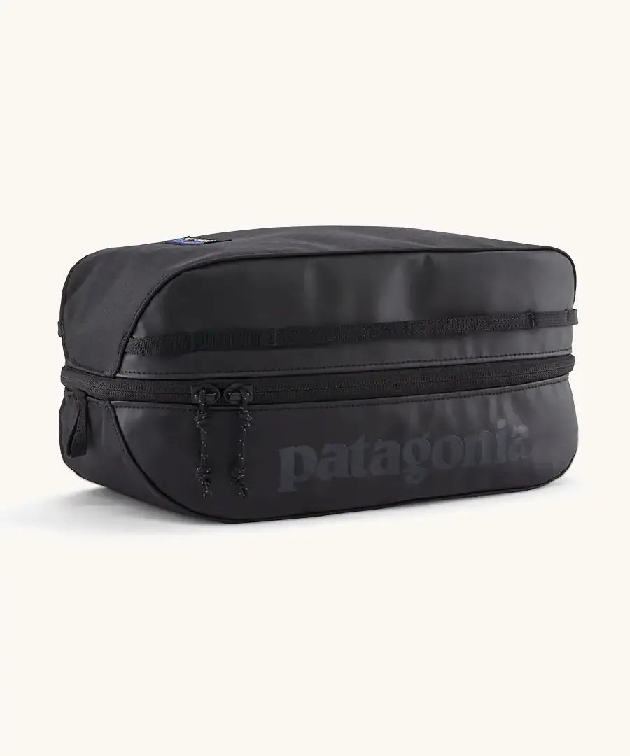 Patagonia black hole 6 litre cube bag in all black with a double zip fastener showing the brand print on front panel