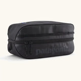 Patagonia black hole 6 litre cube bag in all black with a double zip fastener showing the brand print on front panel